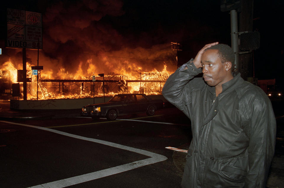 Businessman holds hand to head as store burns