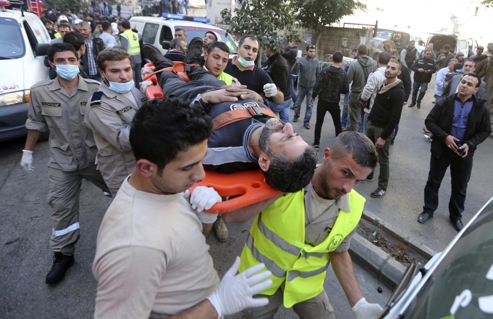 Civil defence personnel and medics transport a wounded man on a stretcher at a site of an explosion in the Haret Hreik area, in the southern suburbs of the Lebanese capital Beirut