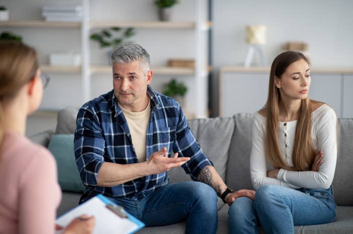 Unhappy mature couple having meeting with marital counselor, discussing relationship problems. Middle-aged spouses sitting on couch at therapist's office in need of professional help