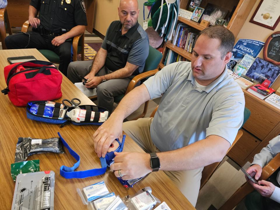 Robert Baran, director of emergency services in Manchester, demonstrates how materials in a first aid kit could staunch bleeding during an emergency in a school. Central Regional Middle School Principal Joseph Firetto looks on.