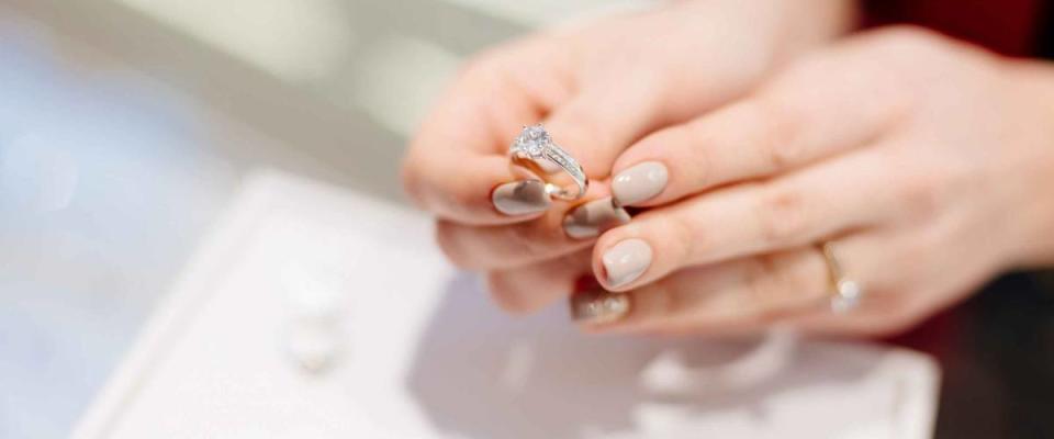 Female seller in a luxury jewelry store presents a ring. Buying a engagement ring. Jewelry store. Woman jeweler.