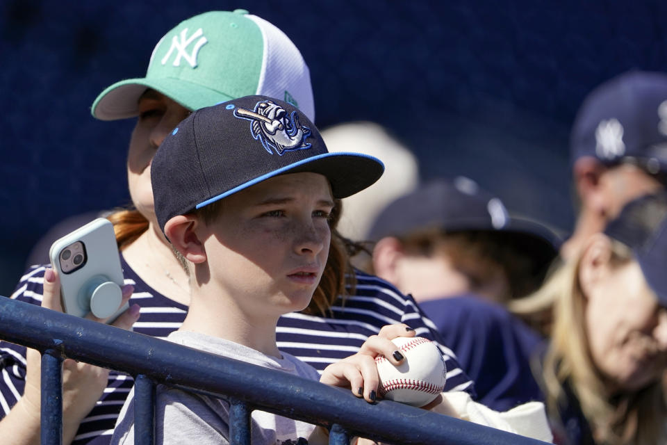 A young fan watches New York Yankees players during a spring training baseball workout, Monday, March 14, 2022, in Tampa, Fla. (AP Photo/John Raoux)