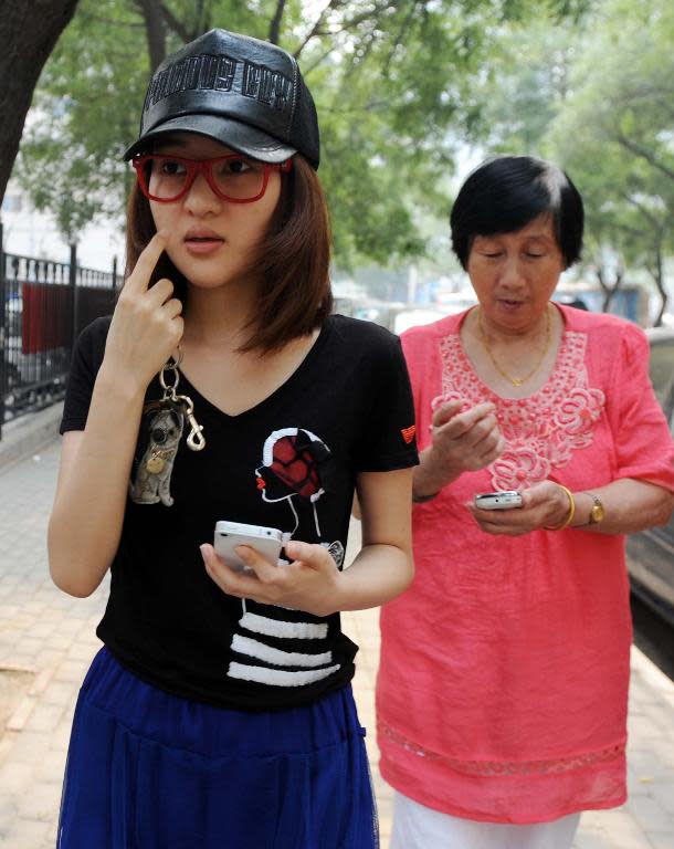 Picture taken on August 21, 2011 shows actor and singer Guo Meimei (C) walking away from a police station with her grandmother after reporting her and her family members being harrassed by strangers in Beijing