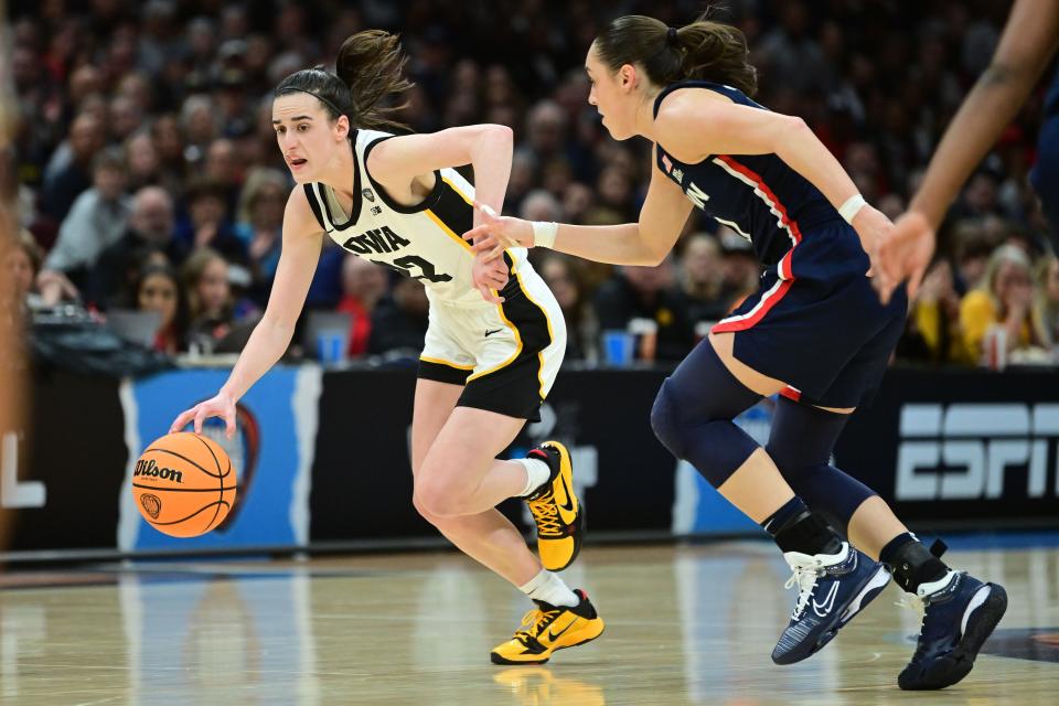 Iowa guard Caitlin Clark (22) dribbles the ball past Connecticut Huskies guard Nika Muhl (10) during Friday's national semifinal game.