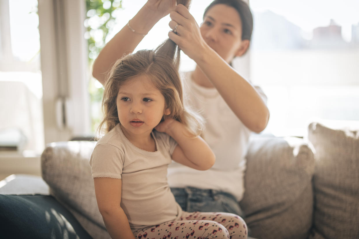 Mother doing head lice cleaning on daughter at home