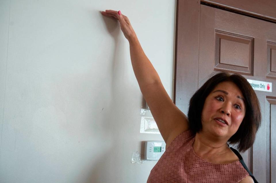 Owner Kim Pham holds up her hand to demonstrate how high the water came up inside her restaurant during Hurricane Katrina at Kim Long in Biloxi on Wednesday, Aug. 2, 2023. Hannah Ruhoff/Sun Herald