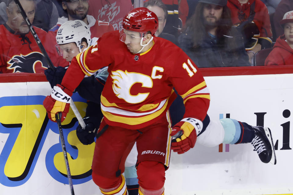Calgary Flames' Mikael Backlund, right, hits Seattle Kraken's Eeli Tolvanen during the first period of an NHL hockey game Wednesday, Dec. 27, 2023, in Calgary, Alberta. (Larry MacDougal/The Canadian Press via AP)