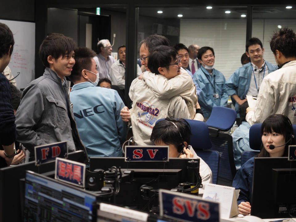 In this photo provided by the Japan Aerospace Exploration Agency (JAXA), staff of the Hayabusa2 Project react as they confirm Hayabusa2 made a maneuver at the control room of the JAXA Institute of Space and Astronautical Science in Sagamihara, near Tokyo, Friday, Feb. 22, 2019. The Japanese spacecraft has made a touchdown on a distant asteroid on a mission to collect material that could provide clues to the origin of the solar system and life on Earth.(ISAS/JAXA via AP)