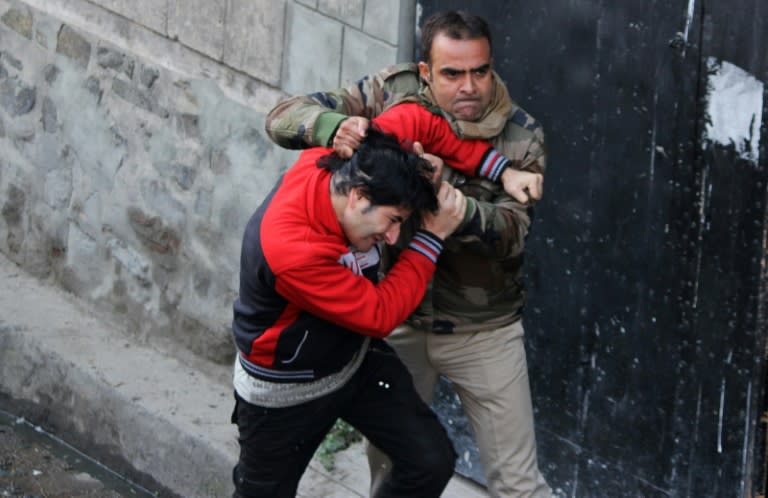 An Indian police official scuffles with a Kashimiri youth after the firefight in Srinagar