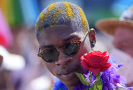 A participant of the Cologne Pride rally is pictured with a red rose in Cologne, Germany, Sunday, July 3, 2022. This year's Christopher Street Day (CSD) Gay Parade with thousands of demonstrators for LGBTQ rights is the first after the coronavirus pandemic to be followed by hundreds of thousands of spectators in the streets of Cologne. (AP Photo/Martin Meissner)