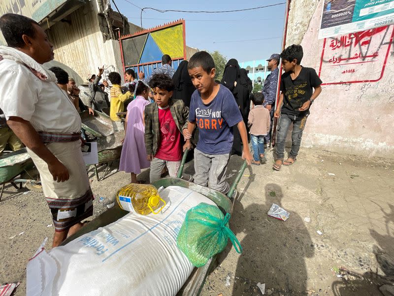 Boy pushes a wheel cart with wheat flour, cooking oil and beans at an aid distribution center in Sanaa