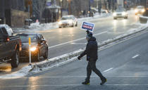 A supporter of Sen. Mitt Romney's, R-Utah, recent vote, takes his message across the street as people gather at the Wallace F. Bennett Federal Building in Salt Lake City, Utah, on Wednesday, Feb. 5, 2020. Republicans in the state are unusually divided on the president, so while some were heartened to see Romney cast what he described as an agonizing vote dictated by his conscience, Trump supporters were left angry and frustrated. (Francisco Kjolseth/The Salt Lake Tribune via AP)