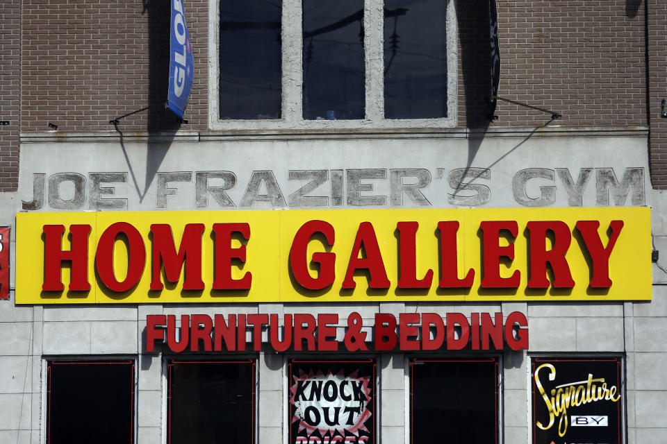 The façade of a furniture store is over the original sign for the gym where heavyweight champ Joe Frazier lived and trained, on Tuesday, April 30, 2013, in Philadelphia. The building has been named to the National Register of Historic Places. (AP Photo/Matt Rourke)