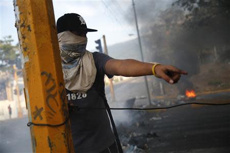 An opposition demonstrator ties up a cable to build a barricade during protest against Nicolas Maduro's government in San Cristobal, about 410 miles (660 km) southwest of Caracas, February 26, 2014. REUTERS/Carlos Garcia Rawlins