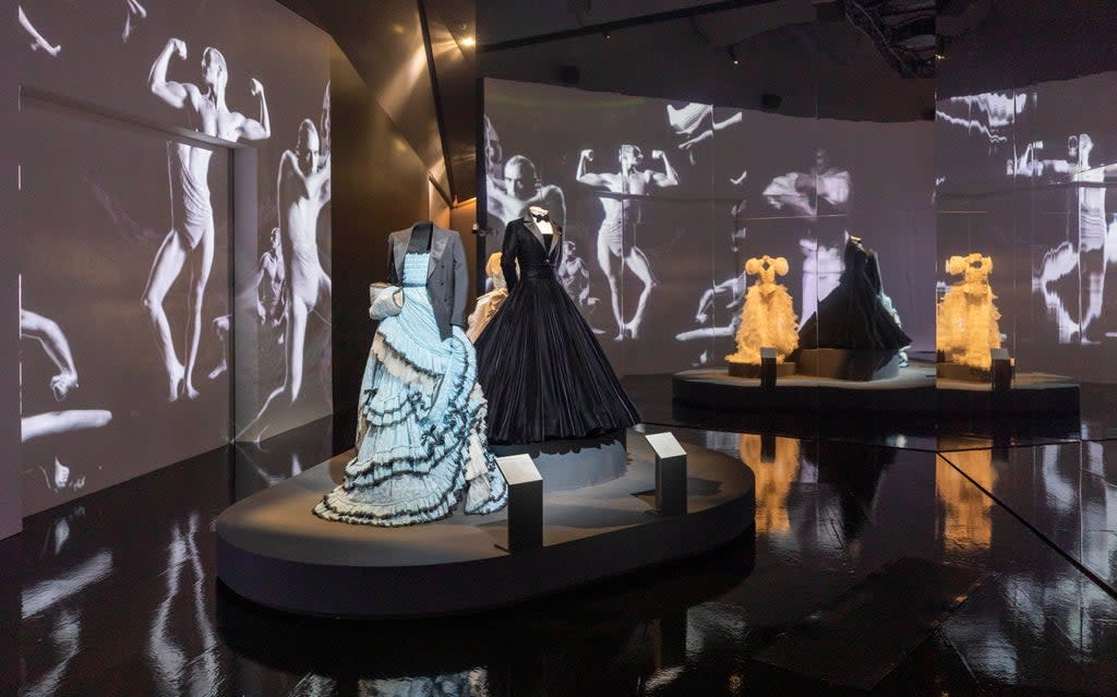 Alessandro Michele for Gucci gown and tailored jacket worn by Harry Styles, Christian Siriano tuxedo gown worn by Billy Porter, and Ella Lynch wedding dress worn by Bimini Bon Boulash. Film by Quentin Jones with Cadence Films. Installation view, finale of Fashioning Masculinities: The Art of Menswear at V&A  (Victoria and Albert Museum, London)