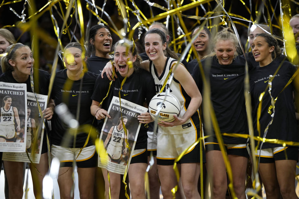 FILE - Iowa guard Caitlin Clark (22) stands with teammate after being presented with a commemorative basketball after the team's NCAA college basketball game against Michigan, Thursday, Feb. 15, 2024, in Iowa City, Iowa. Clark broke the NCAA women's career scoring record. While Clark has done her part with every step-back logo 3-pointer she makes, a generation of women cleared the way for her and others. (AP Photo/Matthew Putney, File)