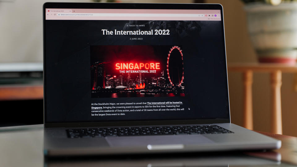 Macbook on a table with screen showing The Dota 2 International 2022 webpage