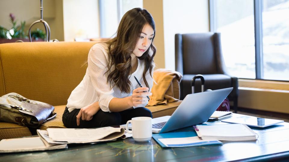 Businesswoman working at laptop in lobby.