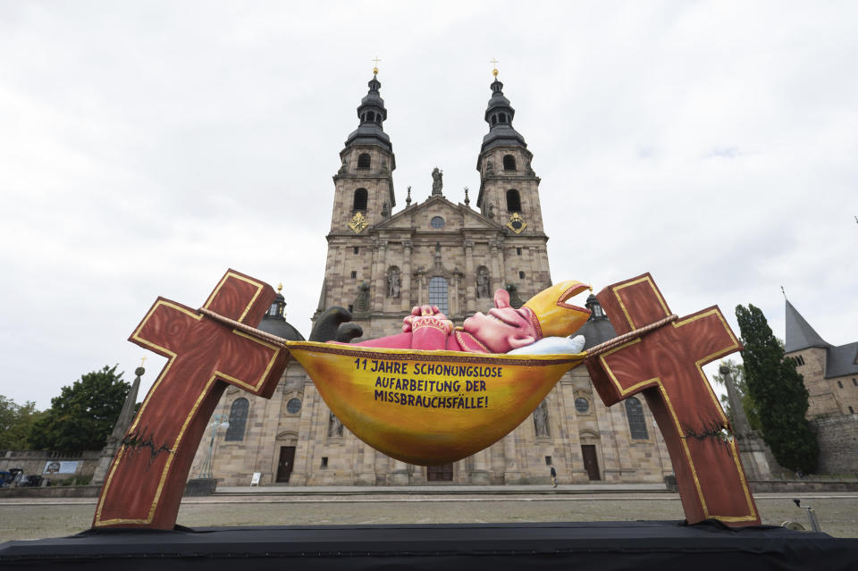 The large sculpture "The Hammock Bishop" by Jacques Tilly stands in front of the cathedral at the beginning of the autumn plenary meeting of the German Bishops' Conference in Fulda, Germany, during a protest action by the Action Alliance of Victims Initiatives and the Giordano Bruno Foundation, Monday, Sept. 20, 2021. The protest action criticizes the handling of victims of sexual abuse in the Catholic Church. The autumn plenary assembly will take place from 20 to 23 September 2021. (Sebastian Gollnow/dpa via AP)