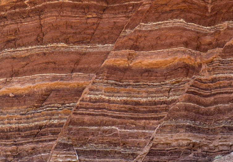 The side of rocks showing lines of different types of rock and fault lines.