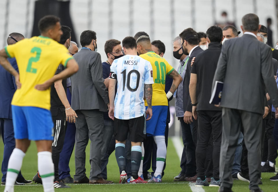 Lionel Messi y Neymar charlan con un agente sanitario luego que el partido entre Argentina y Brasil por las eliminatorias del Mundial fue interrumpido, el domingo 5 de septiembre de 2021. (AP Foto/Andre Penner)