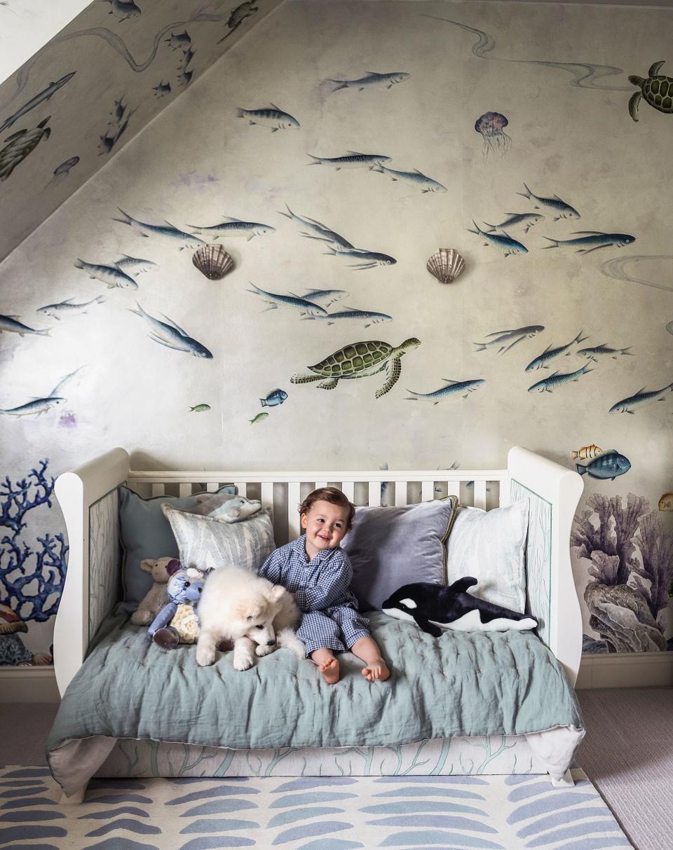 George with Gyda, a samoyed, in his bedroom. De Gournay hand-painted wallpaper; on bed, Robert Allen linen-cotton.