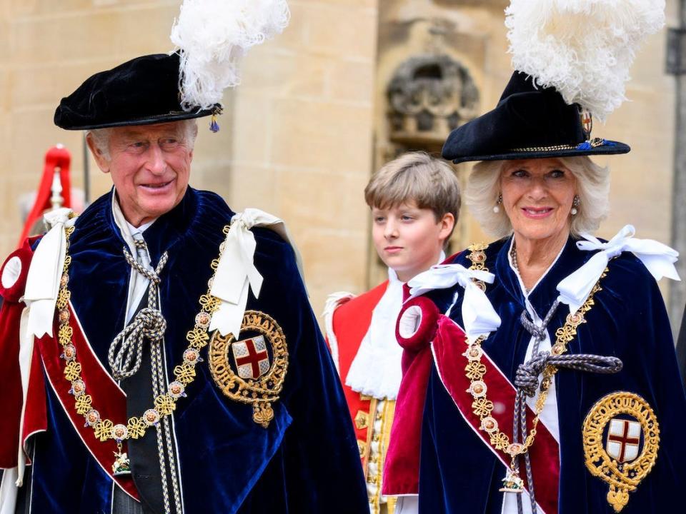 Prince Charles (left) and Camilla, Duchess of Cornwall (right), wear traditional dress and hats with feathers at the Order of the Garter procession in Windsor, England, on June 13, 2022.