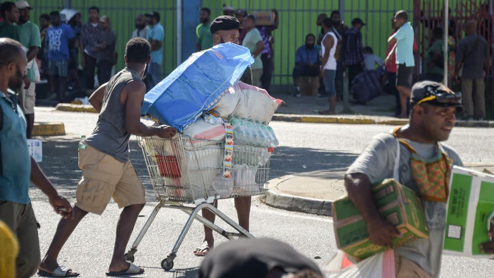 Crowds on the streets of Port Moresby leave shops with bags of looted supplies and goods. - Andrew Kutan/AFP/Getty Images