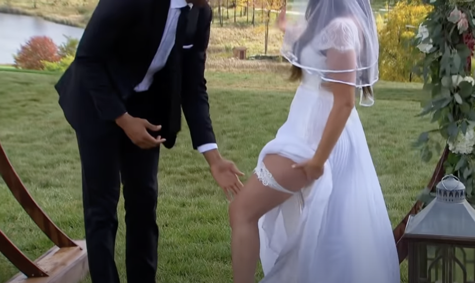 closeup of a groom reaching for the garter on the bride's leg