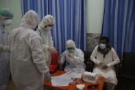 Health officials in protective gear take a sample from a man at a screening and testing facility for COVID-19 in Peshawar, Pakistan, Wednesday, June 3, 2020. (AP Photo/Muhammad Sajjad)