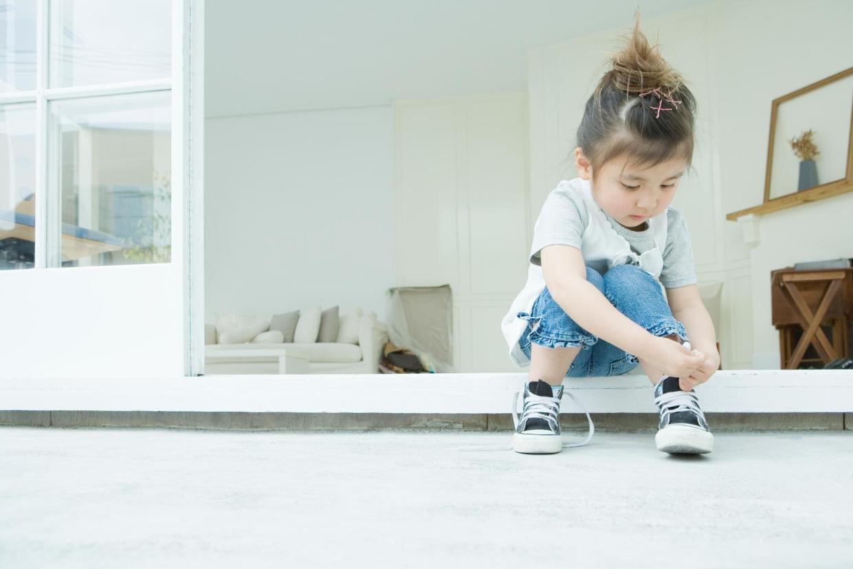 Girl learning to tie her shoelaces