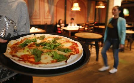 A waitress serves pizza at a restaurant in Moscow, September 10, 2014. REUTERS/Maxim Zmeyev