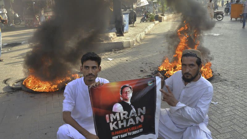 Supporters of former Pakistan Prime Minister Imran Khan hold a banner of their leader next to burning tires during a protest to condemn the arrest of their leader, in Hyderabad, Pakistan, Tuesday, May 9, 2023. Khan was arrested Tuesday as he appeared in a court in the country’s capital, Islamabad, to face charges in multiple graft cases. Security agents dragged Khan outside and shoved him into an armored car before whisking him away.