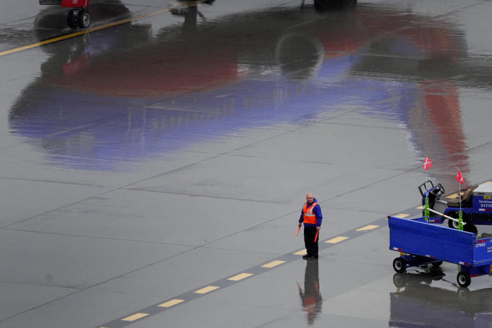 A Southwest Airlines ground operations crew member waits to guide an arriving jet into a gate, Wednesday, Dec. 28, 2022, at Sky Harbor International Airport in Phoenix. (AP Photo/Matt York)