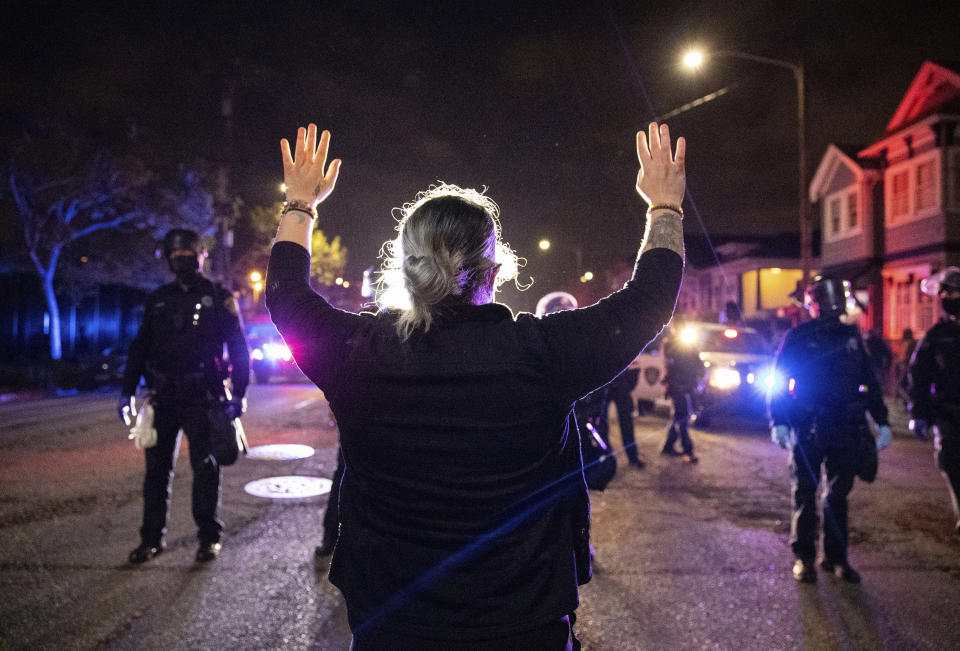 A demonstrator confronts a line of Oakland police officers during a protest against police brutality in Oakland, Calif., on Friday, April 16, 2021. (AP Photo/Ethan Swope)