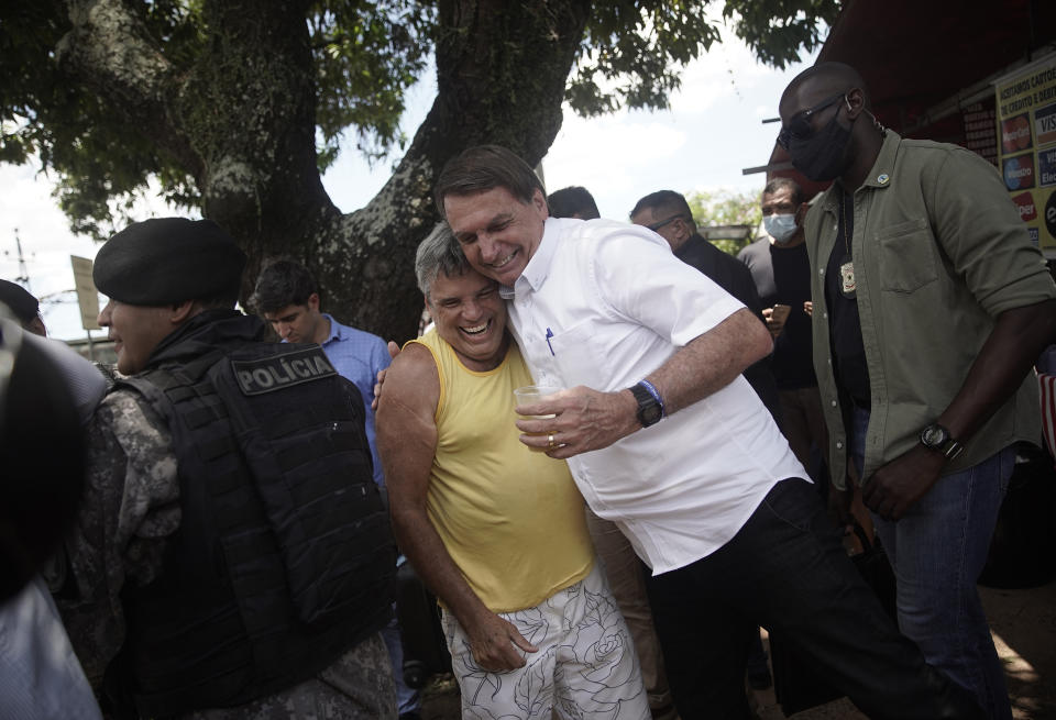 Brazil's President Jair Bolsonaro embraces a supporter after voting during the run-off municipal elections in Rio de Janeiro, Brazil, Sunday, Nov. 29, 2020. Bolsonaro, who sometimes has embraced the label "Trump of the Tropics," said Sunday he'll wait a little longer before recognizing the U.S. election victory of Joe Biden. (AP Photo/Silvia Izquierdo)