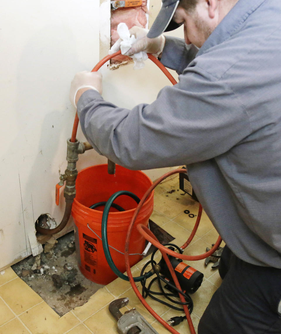 FILE - In this Jan. 9, 2014 file photo, Roto Rooter plumber Nate Petersen pumps water into the incoming city water line that has been frozen at a south Minneapolis home. In 2013, all winter storm-related insurance losses totaled about $1.9 billion, according to the Insurance Information Institute. That includes damage from frozen pipes. (AP Photo/Jim Mone, File)