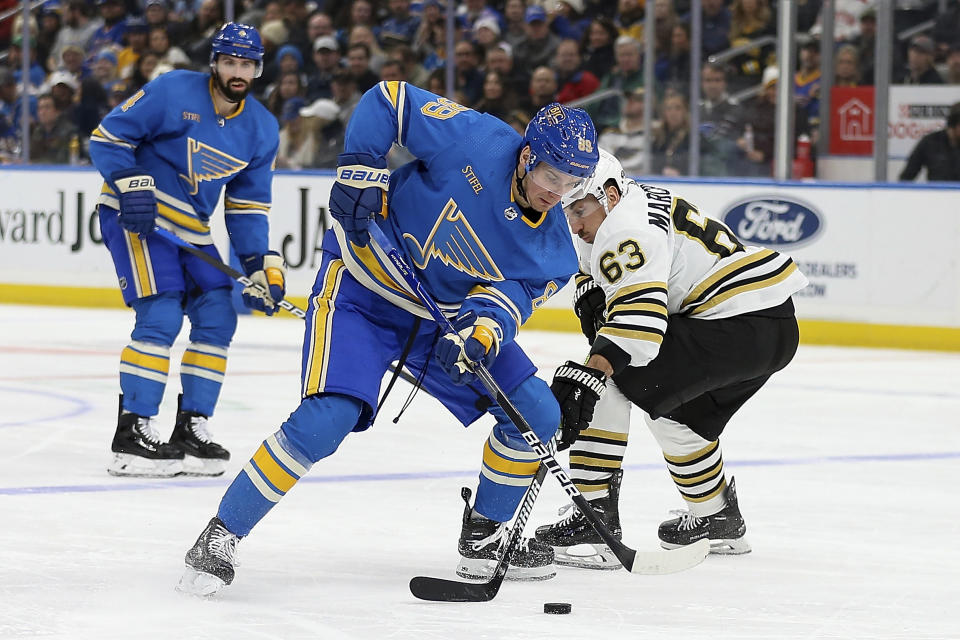 St. Louis Blues' Pavel Buchnevich (89) and Boston Bruins' Brad Marchand (63) vie for control of the puck during the second period of an NHL hockey game Saturday, Jan. 13, 2023, in St. Louis. (AP Photo/Scott Kane)