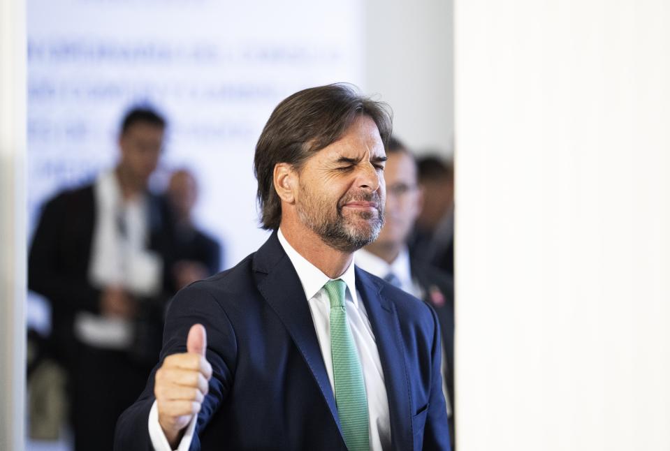 Uruguay's President Luis Lacalle Pou winks and flashes a thumbs up as he exits a meeting during the Mercosur trade bloc summit, in Montevideo, Uruguay, Tuesday, Dec. 6, 2022. (AP Photo/Matilde Campodonico)