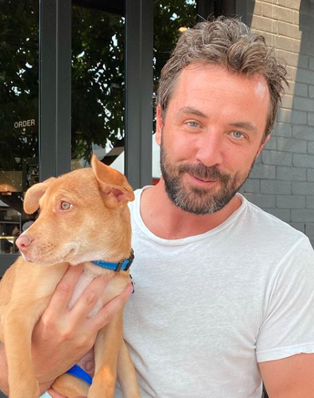 Darren McMullen poses with a dog in a blue collar