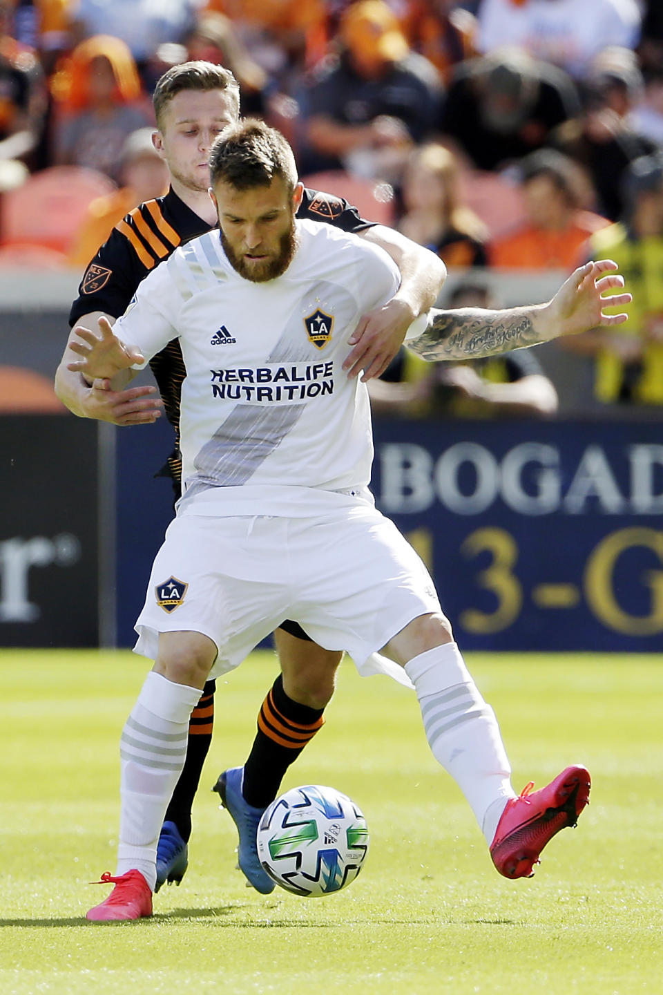 Los Angeles Galaxy midfielder Aleksandar Katai, front, shields the ball from Houston Dynamo defender Adam Lundkvist during the first half of an MLS soccer match Saturday, Feb. 29, 2020, in Houston. (AP Photo/Michael Wyke)