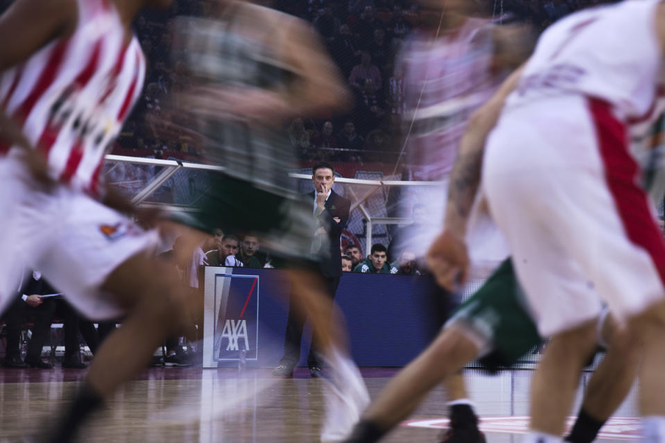 In this image taken with a slow shutter speed, Panathinaikos coach Rick Pitino, center, looks on during a Euroleague basketball match between Panathinaikos and Olympiakos in Piraeus near Athens, on Friday, Jan. 4, 2019. (AP Photo/Petros Giannakouris)