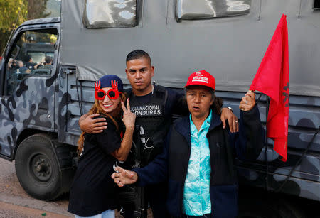 A police officer poses with demonstrators outside the headquarters of Honduras' elite police force, after an agreement with the government not to crack down on demonstrators in the marches over a contested presidential election, according to local media, in Tegucigalpa, Honduras December 5, 2017. REUTERS/Henry Romero