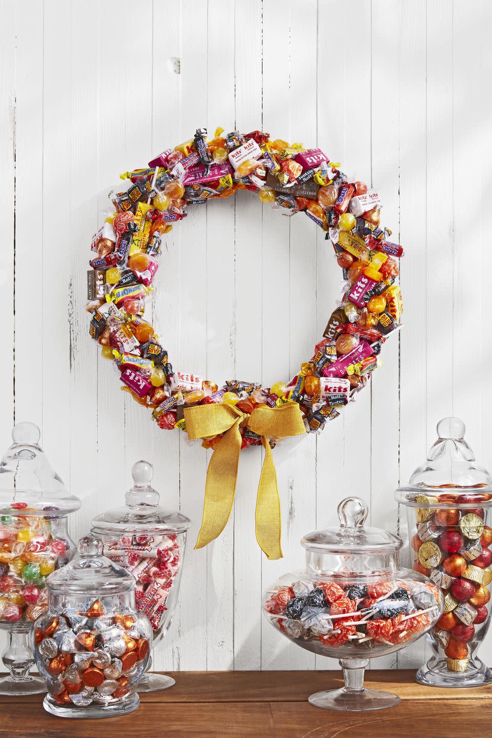 <p>Hang on the door for decoration or let trick-or-treaters help themselves to a sweet treat.<br></p><p>Gather an assortmentof old-fashioned candies in autumnal shades such as yellow, orange, and magenta. Wrap a 14-inch foam wreath form in white ribbon. Attach candy with hot-glue, layering and overlapping as you go. Finish with a yellow burlap bow. </p>