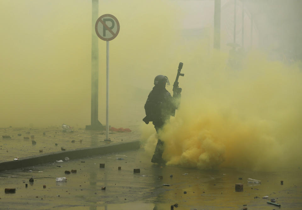 A police officer walks in a cloud of tear gas after dispersing anti-government protesters during a nationwide strike, at Bolivar square in downtown Bogota, Colombia, Thursday, Nov. 21, 2019. Colombia's main union groups and student activists called for a strike to protest the economic policies of Colombian President Ivan Duque government and a long list of grievances. (AP Photo/Fernando Vergara)