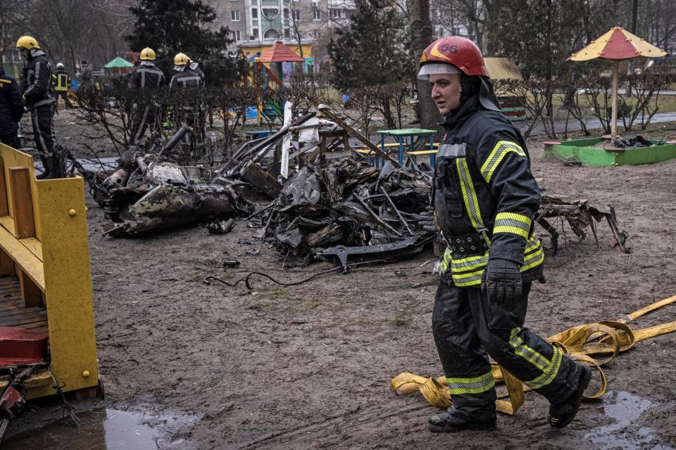 Firemen roll up hoses in front of debris as emergency service workers respond at the site of a helicopter crash on January 18, 2023 in Brovary, Ukraine. Eighteen people have been killed, including Ukraine's interior affairs minister Denys Monastyrsky along with eight other helicopter passengers, after they crashed near a nursery in a Kyiv suburb.