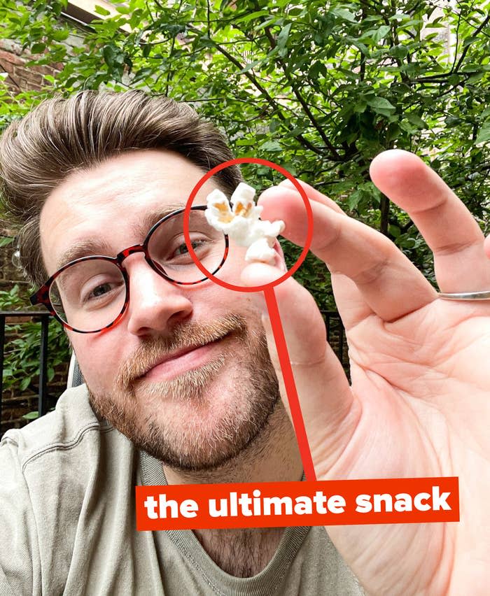 the author showing a piece of popcorn with the words "the ultimate snack"