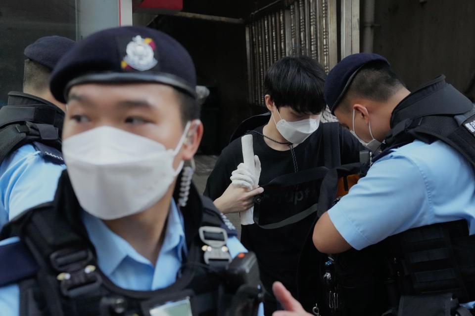 Police officers stop and search a man holding a sculpture near the Hong Kong's Victoria Park, Saturday, June 4, 2022. Dozens of police officers patrolled Hong Kong's Victoria Park on Saturday after authorities for a second consecutive third banned public commemoration of the anniversary of the Tiananmen Square crackdown in 1989, amid a crackdown on dissent in the city. (AP Photo/Kin Cheung)