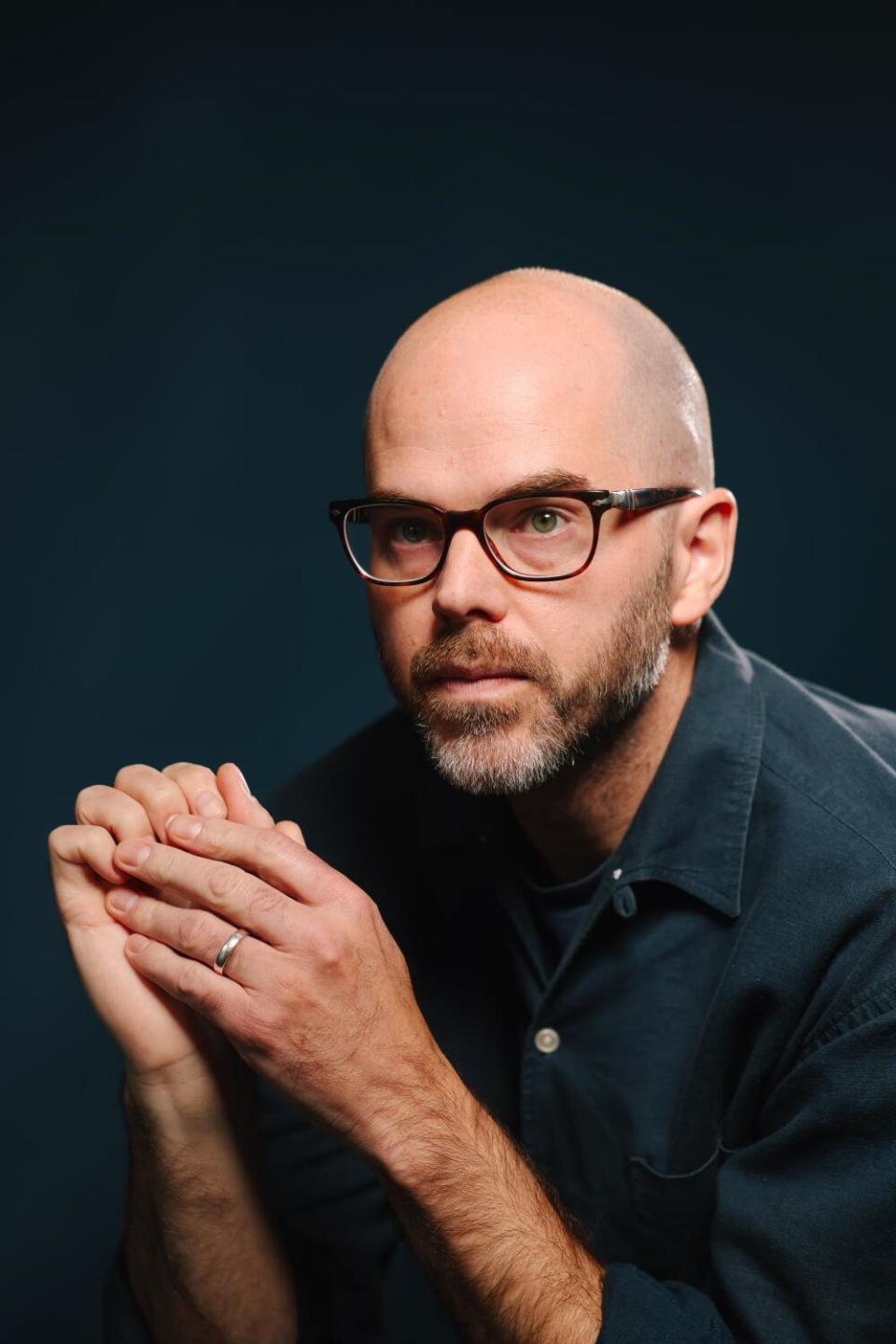 A man poses with his hands touching.