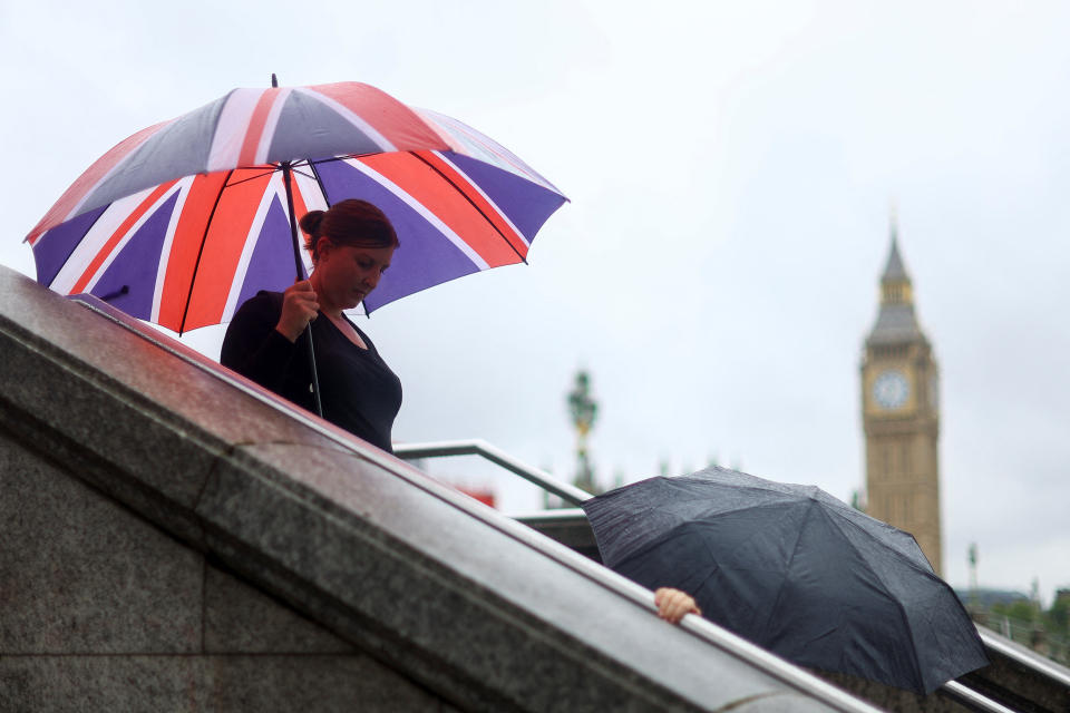UK economy A pedestrian holding an umbrella walks as Elizabeth Tower, more commonly known as Big Ben, is seen in the background after a heavy rain hits London, Britain August 25, 2022. REUTERS/Hannah Mckay